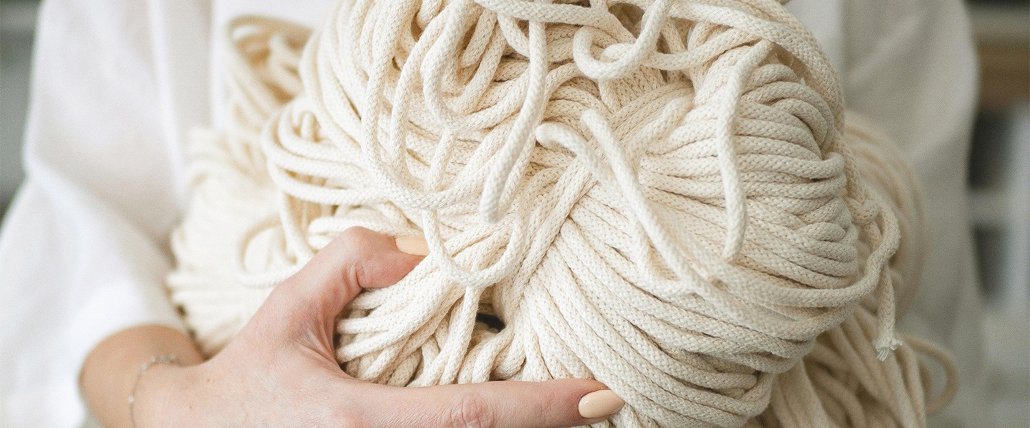 manos sosteniendo una bola de cordón de macramé