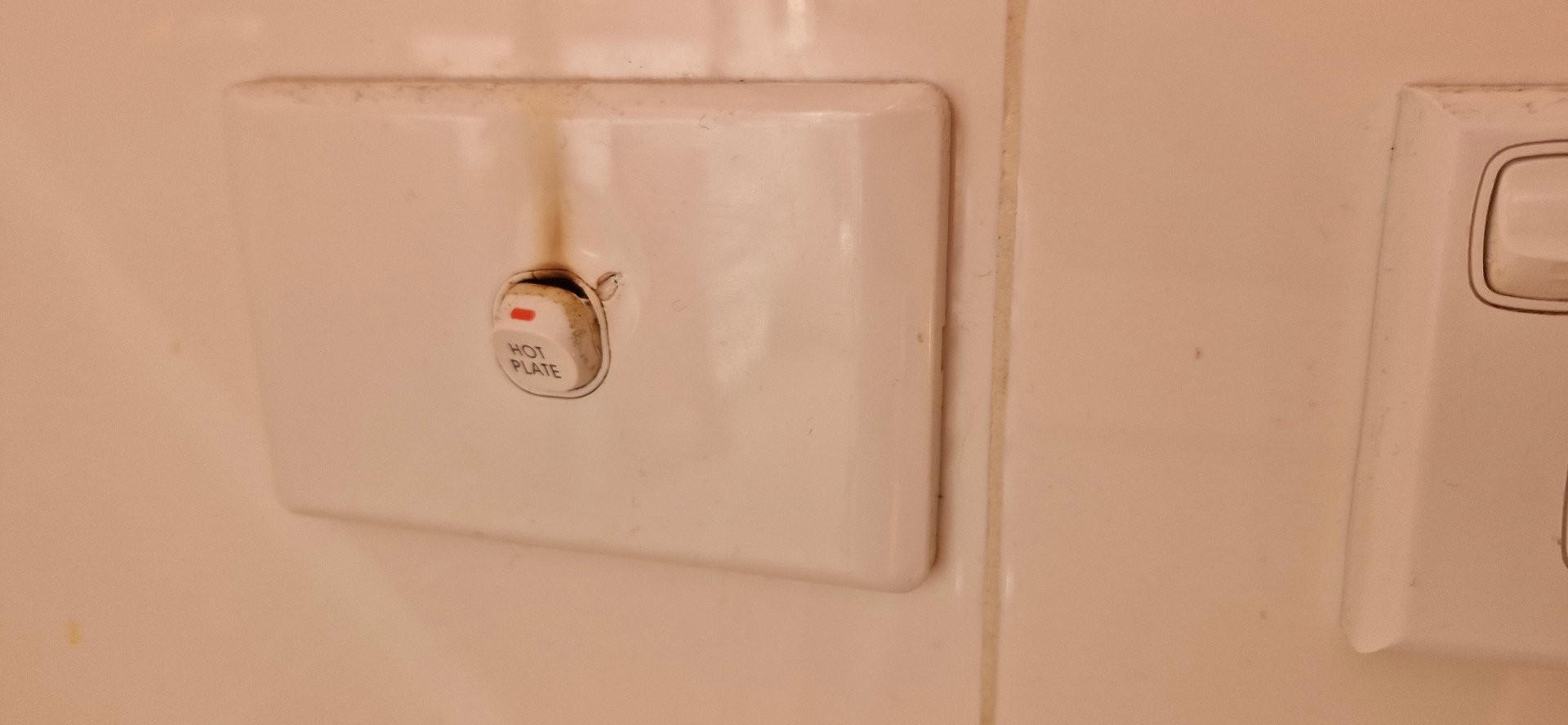 Burned electrical wall switch labeled hot plate showing brown scorch marks from overheating.