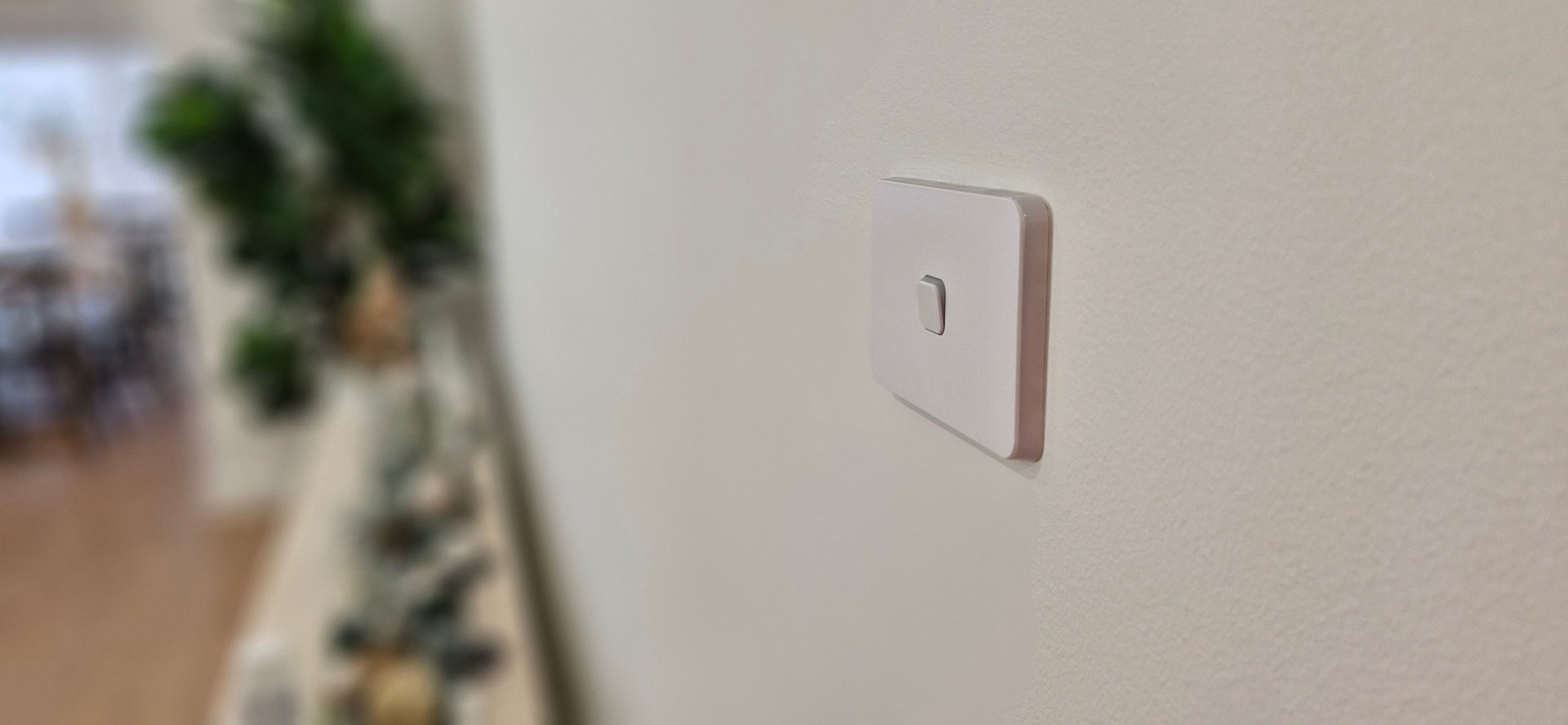 A white light switch on a white wall