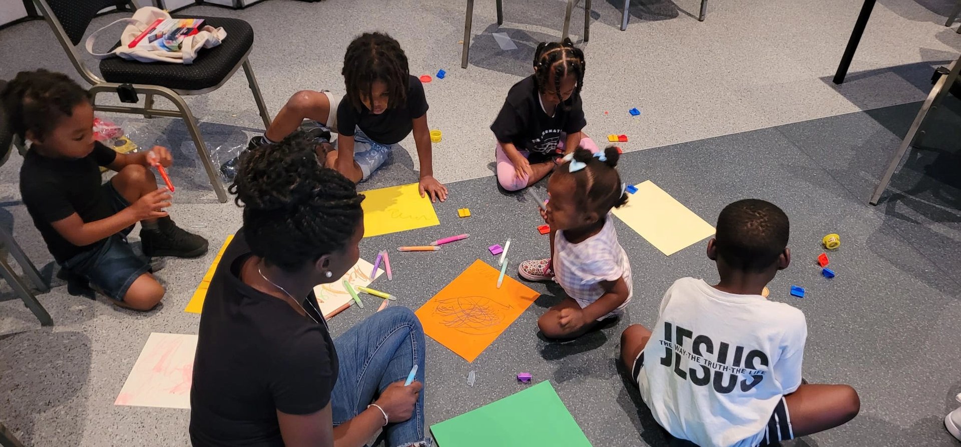 a group of children sitting on the floor in a circle drawing