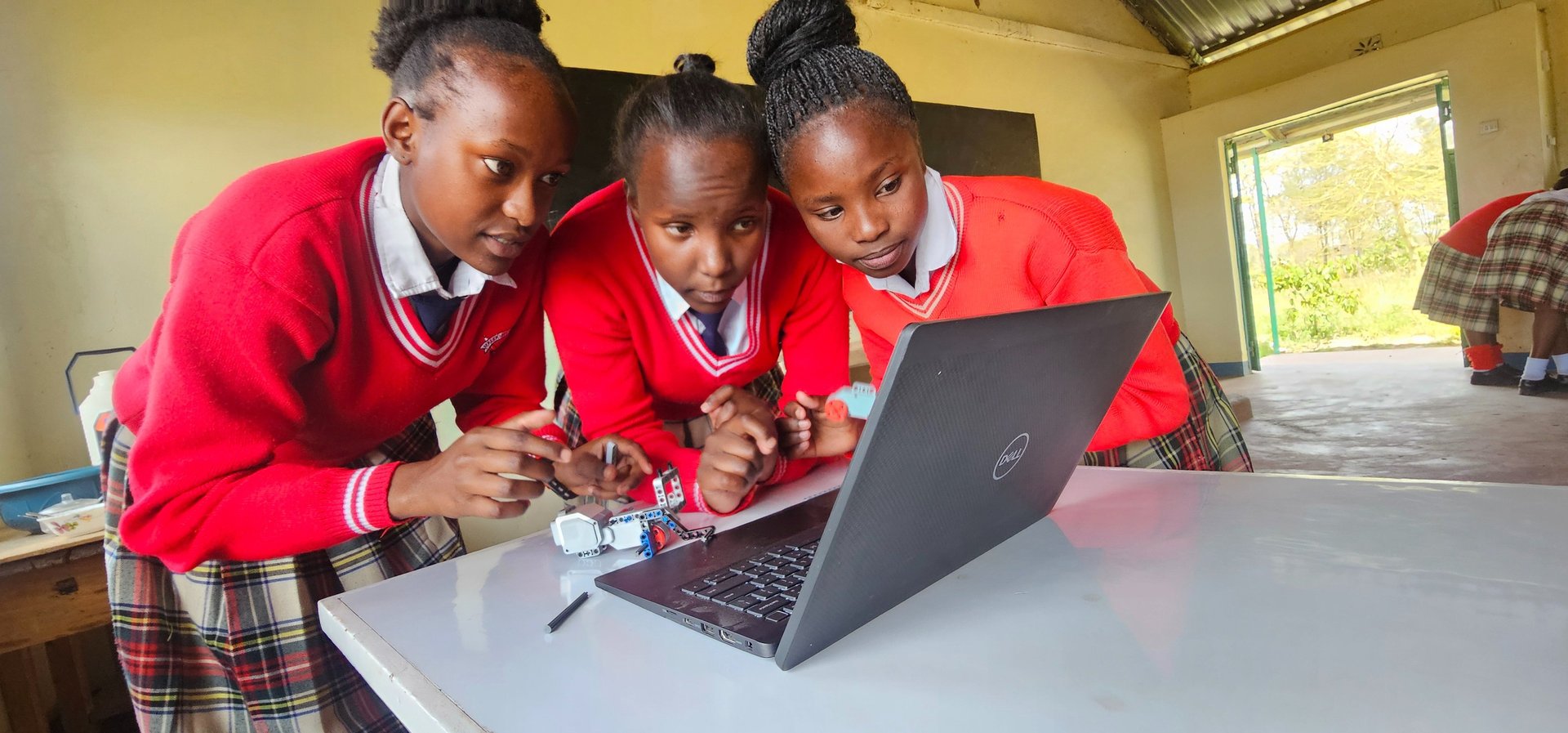 3 Kenyan girls in red sweaters building robots