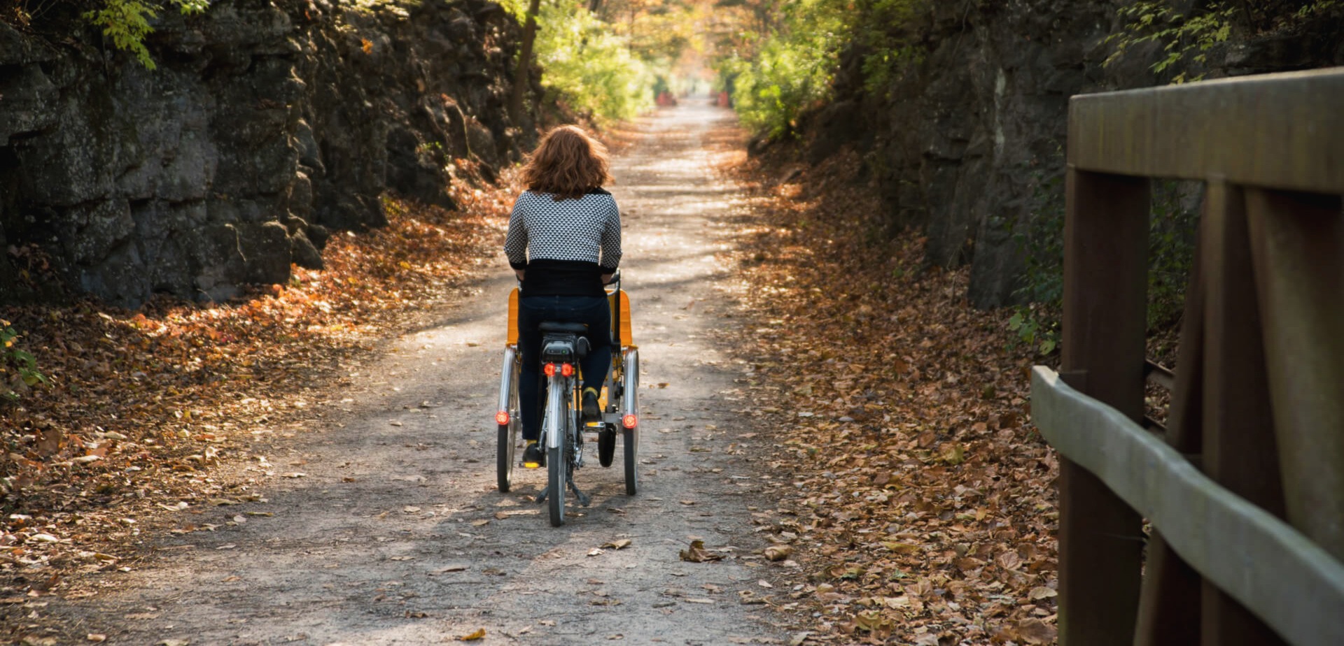 A person pedaling our "Giving Rides Bike" on a gravel trail