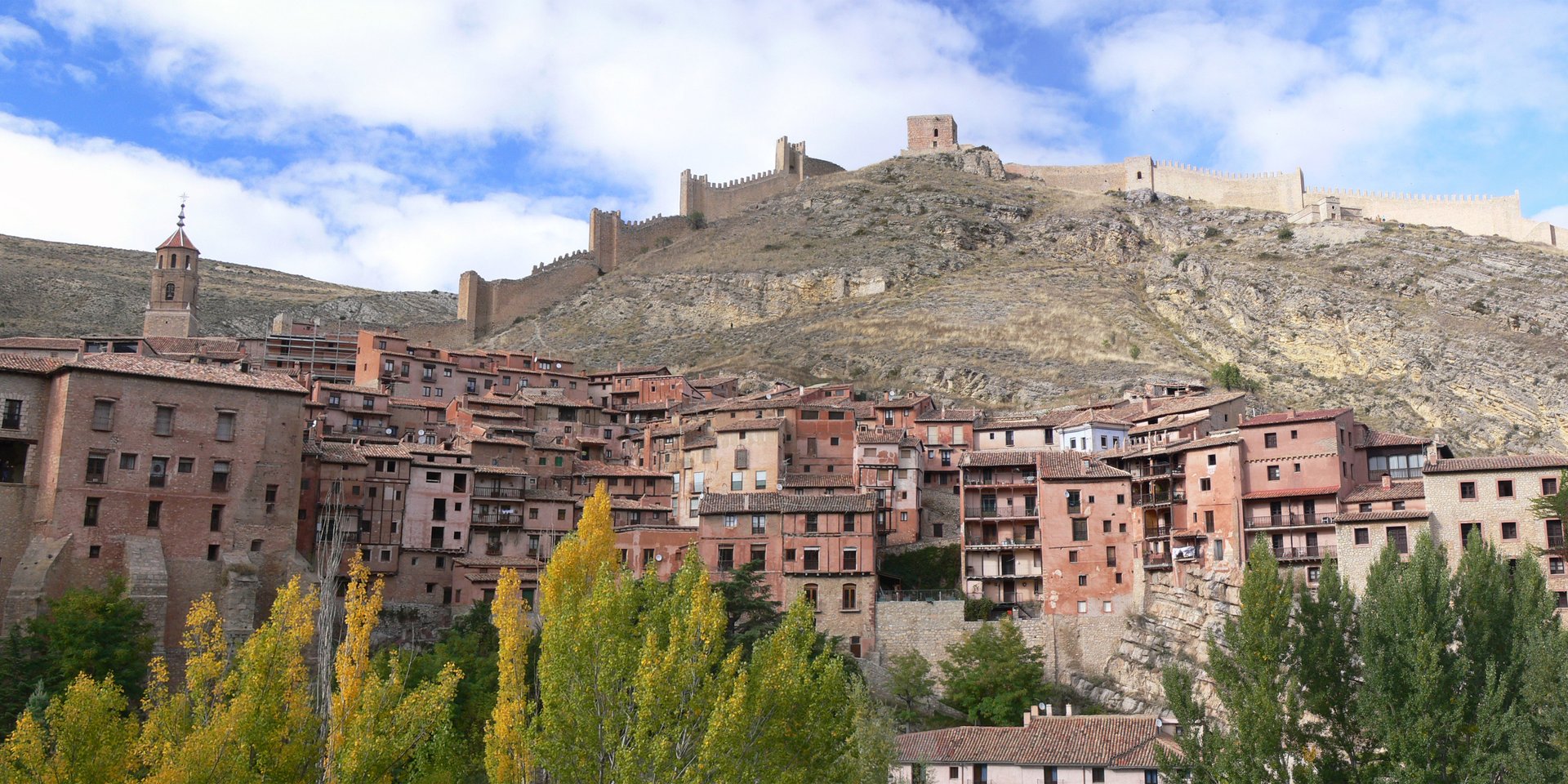 Medieval town of Albarracin with red stone houses and historic castle walls on a Spanish hillside.