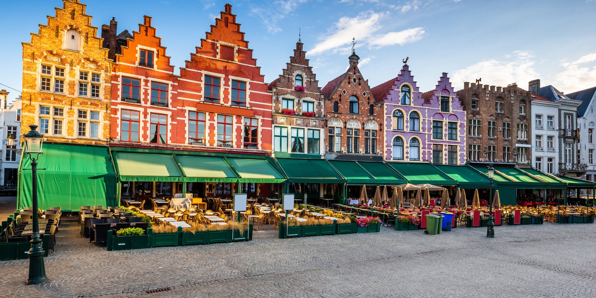 Colorful medieval guildhalls and outdoor cafes at the Market Square in Bruges, Belgium.