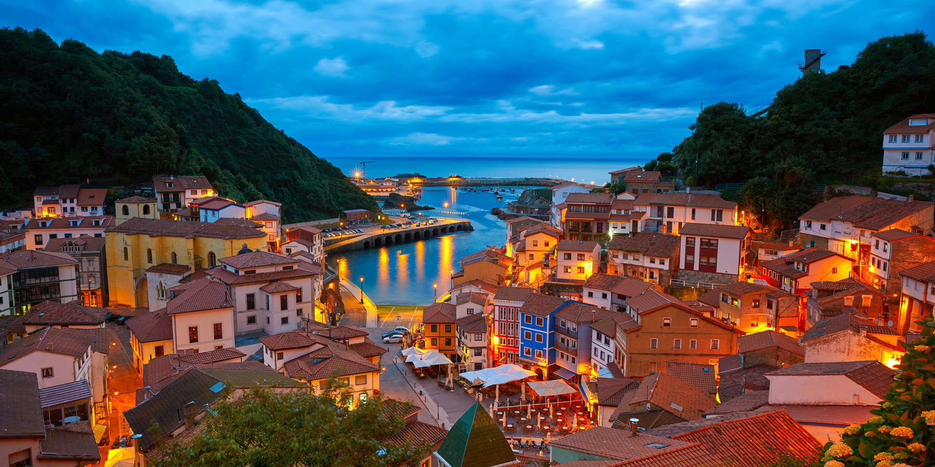 Panoramic evening view of Cudillero fishing village in Asturias, Spain, with colorful houses and harbor.