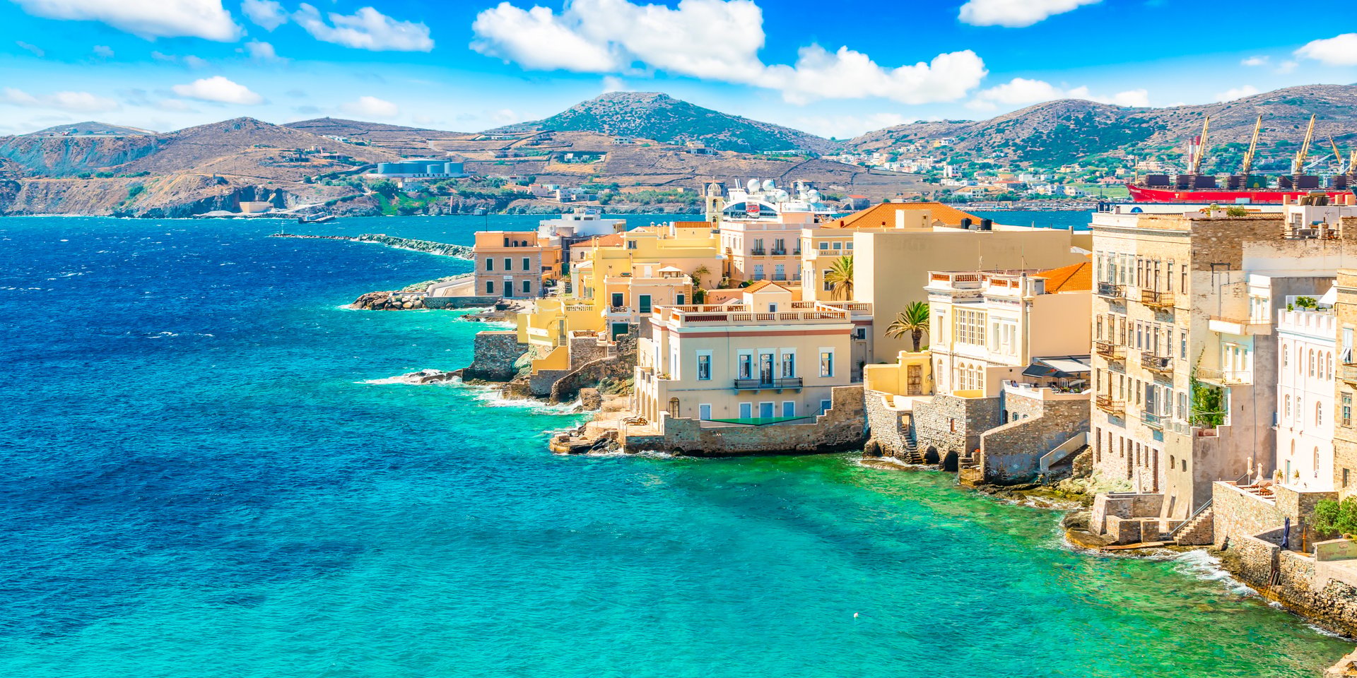 Colorful coastal architecture in Ermoupoli overlooking the turquoise Aegean Sea on Syros island, Greece.
