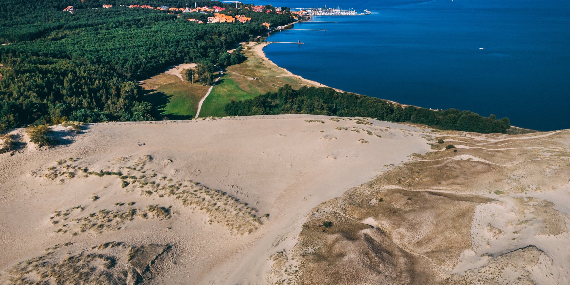 Aerial view of Parnidis Dune in Nida, Lithuania, overlooking the Curonian Lagoon and lush forest.