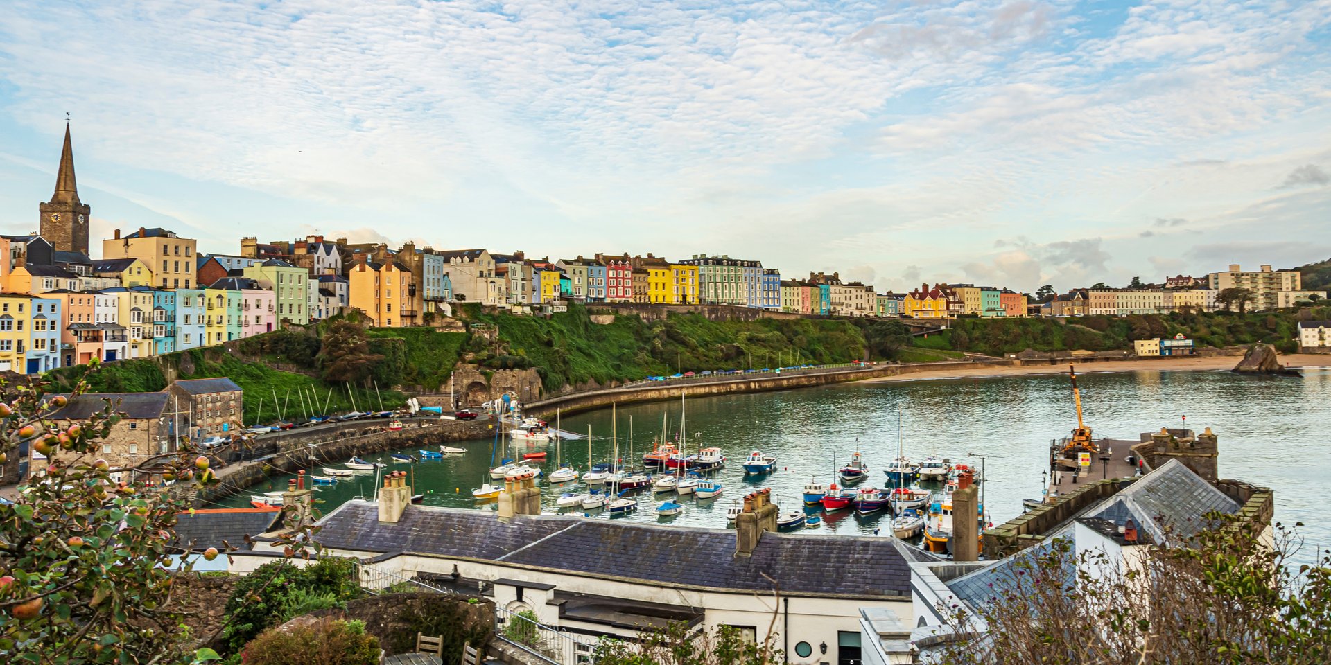 Panoramic view of colorful coastal houses and boats in Tenby Harbour, Pembrokeshire, Wales.