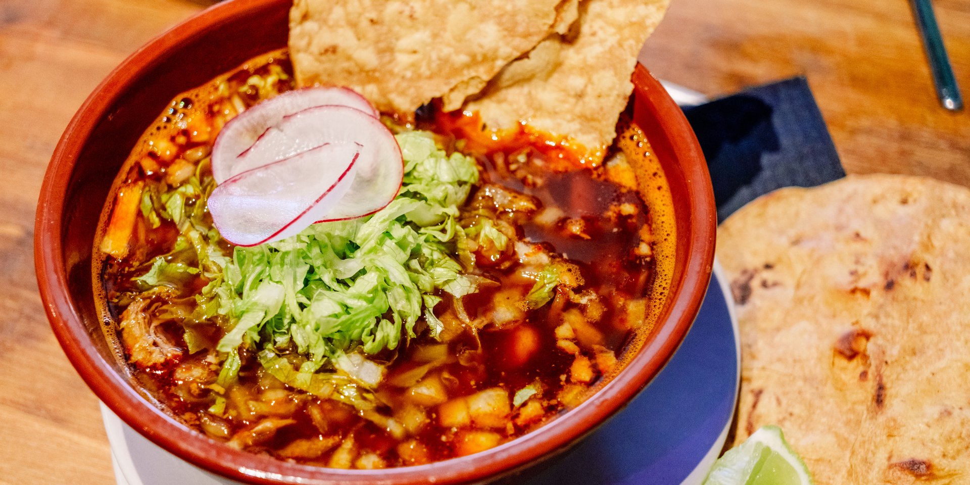 Authentic Mexican pork pozole rojo topped with shredded lettuce, radish, and crispy tostadas.