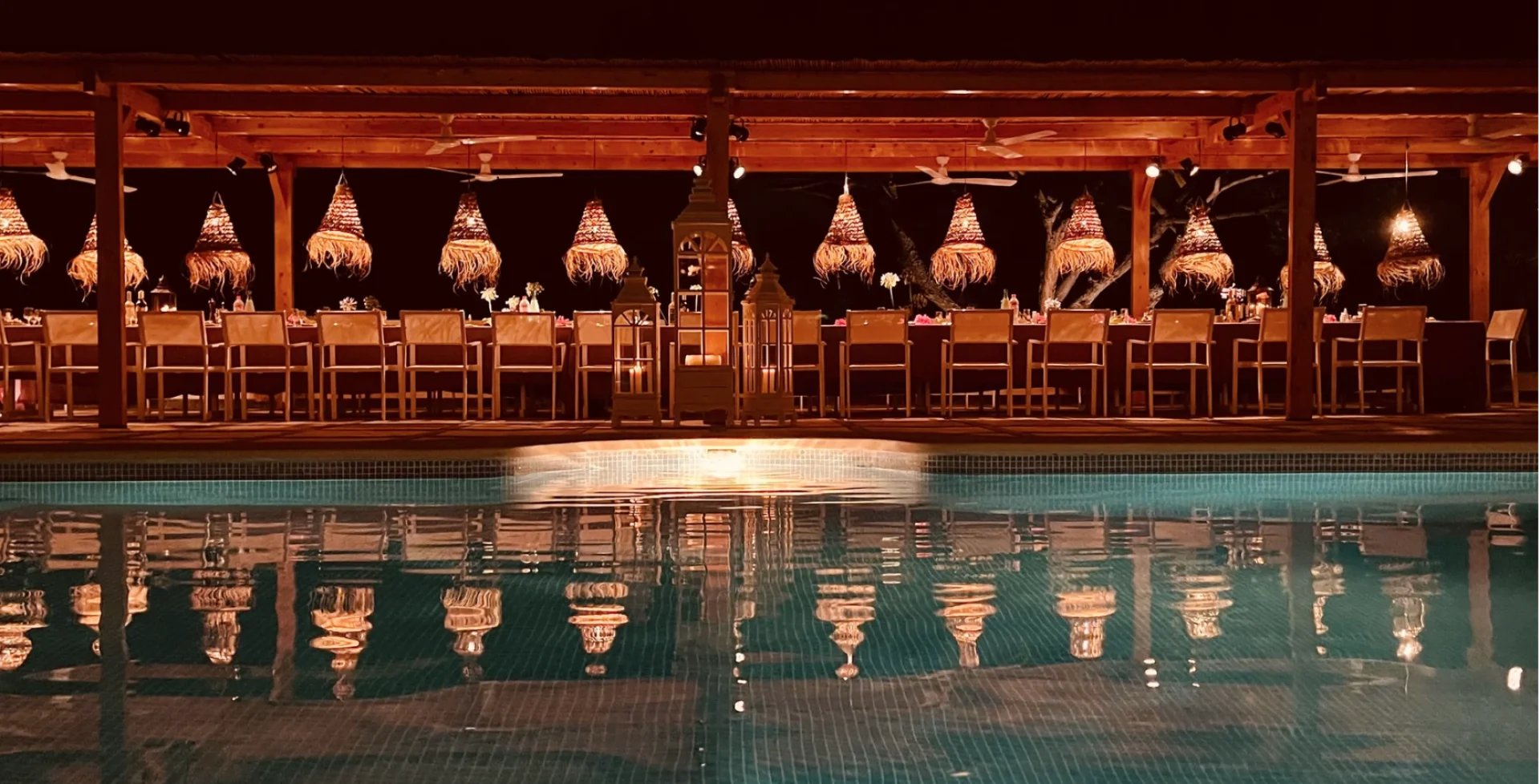 Poolside themed dinner under illuminated wooden pergola