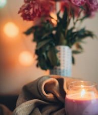 a candle with a vase with flowers