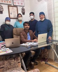 a group of people standing around a table with a laptop