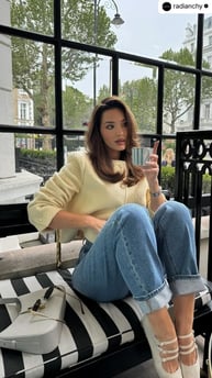 a woman sitting on a bench with a drink