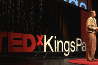 a woman standing on a stage making a TEDx speech