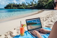 uma mulher sentada na praia com um laptop