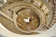 a bride and groom walking down a spiral staircase