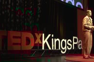 a woman standing on a stage making a TEDx speech