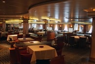 Restaurante elegante a bordo de navio de cruzeiro, com mesas arrumadas.