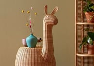 a wicker chair with a vase of flowers in a room