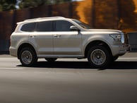 a silver suv driving down a street in the city