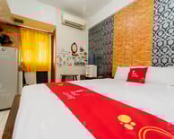 flazale reddoorz flash sale promo a bed with a red and white bedding and a refrigerator