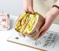 a person holding a sandwich sandwich in a paper bag