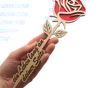 a person holding a wooden rose on a white background