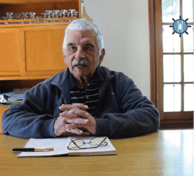 el capitan longa sentado y apoyado en una mesa