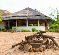 A peaceful image of Tamba Kuruba Eco-Lodge in Kartong, nestled amidst lush greenery and tall trees. 