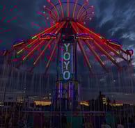 a carnival ride at night with people sitting on chairs