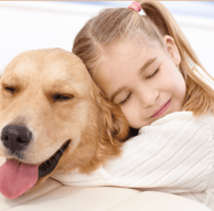 A young girl hugging her golden retriever