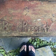 words "Be present" carved into wood