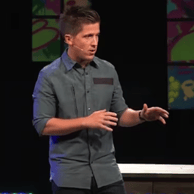 a man standing on a stage speaking to a crowd