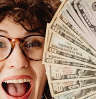 a woman with glasses and a blue shirt holding a stack of money