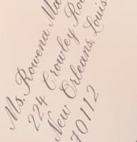 light pink envelope with an address written in calligraphy script in brown ink