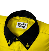 a yellow shirted pillow with a black collar and label