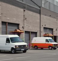 Two cargo vans waiting for a cargo at a facility