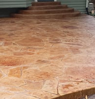A beautiful brick colored stamped concrete patio with formed steps going up to the rear of a house