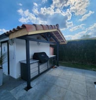 Structure métallique sur mesure pour cuisine extérieure avec auvent en tuiles, conçue par un métallier ferronnier à proximité