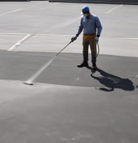 Road markings on asphalt include double yellow lines, indicating no parking restrictions, and several colored spray paint markings in red, white, cyan, and orange, possibly denoting utility lines or underground work.