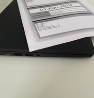 a laptop computer sitting on a desk with a paper document