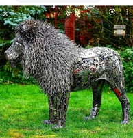 Lion grandeur nature sculpté en métal recyclé, avec détails élaborés sur la crinière, dans jardin