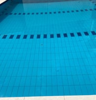 a pool with a blue tiled pool and a white tiled floor