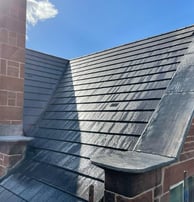 high quality slate roof with copping stones on a parapet wall and chimney 