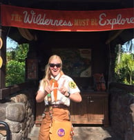 an informal educator in a costume posing in front of a map at Walt Disney World