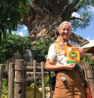 a teacher in a costume is holding a guidebook at Disney's Animal Kingdom in Walt Disney World