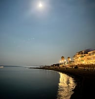 a beachfront of a hotel with a full moon in the sky