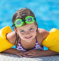 a young girl in a bikinisuit is laying on a swimming pool