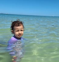 a young girl in a purple swimsuit in the ocean