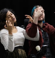 A brown woman and a blue-haired white person in electric wheelchair sign BSL together